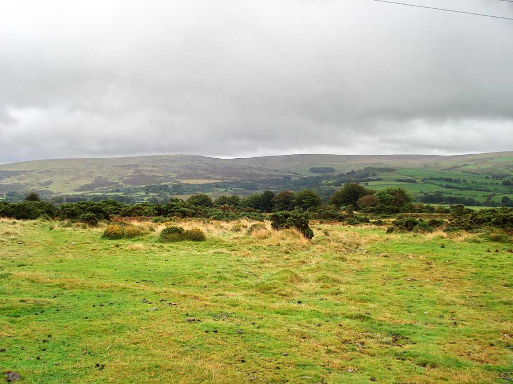 A view across the edge of Kingsett Down to fields beyond with Standon Down in the distance